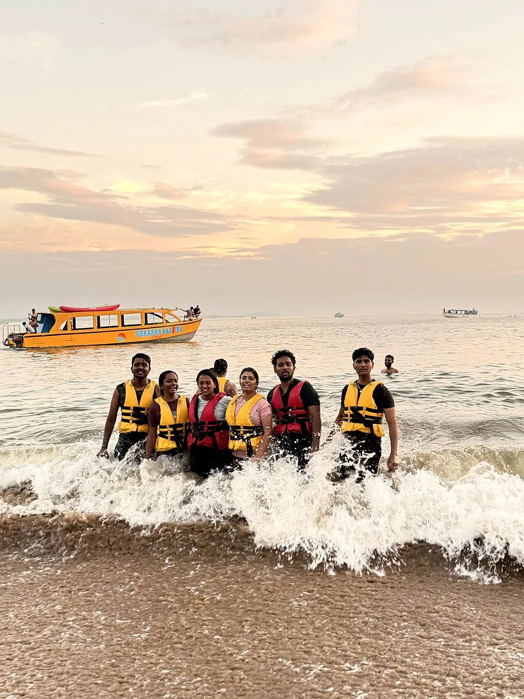 Guests at the water's edge of a hidden beach with the Naavika boat